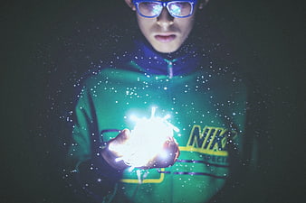 Young man holding glowing fairy lights with magical sparkles