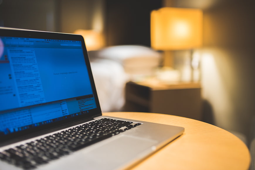Laptop on wooden table in hotel room at night