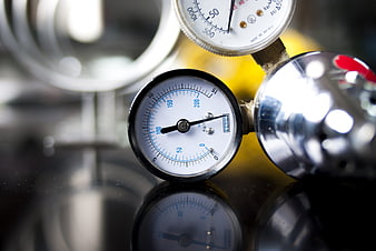 Close-up of industrial pressure gauges on a reflective surface