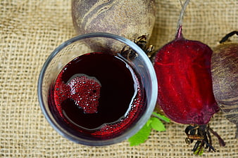 Fresh beetroot juice in glass with raw beets on burlap