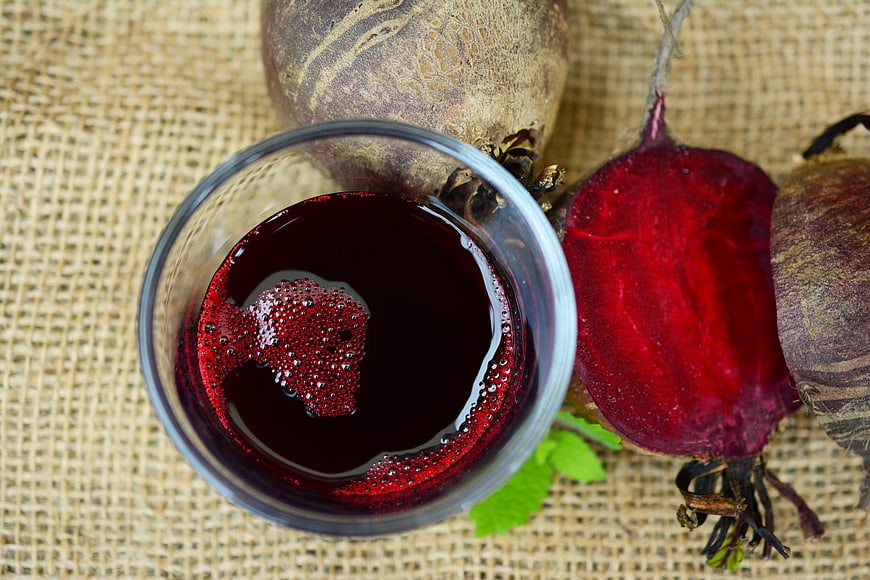 Fresh beetroot juice in glass with raw beets on burlap