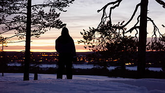 Silhouette of Person Watching Winter Sunset Over Snowy Town