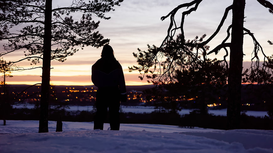 Silhouette of Person Watching Winter Sunset Over Snowy Town