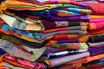 Stack of colorful woven textiles and patterned fabrics