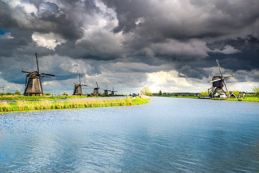 Dramatic Dutch Windmills Along Canal Under Stormy Sky