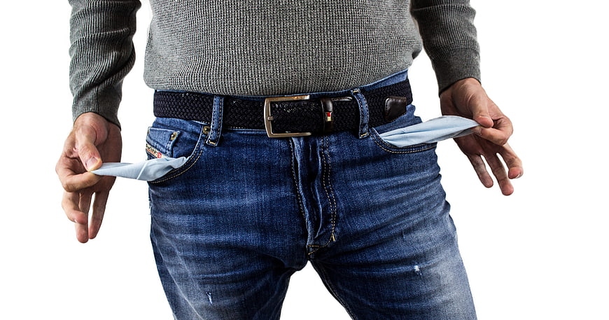 Man turning out empty pockets on white background