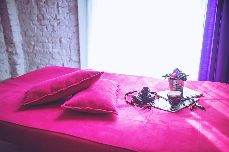 Vibrant pink bed with vintage camera and coffee cup