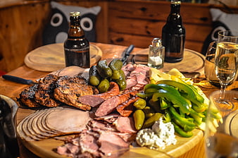 Rustic wooden charcuterie board with smoked meats, pickles, and beer