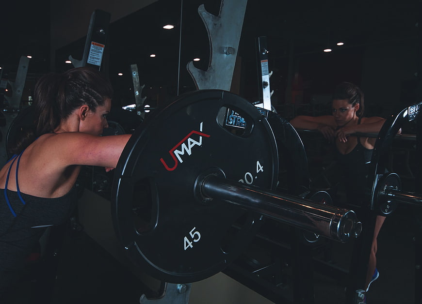 Woman performing barbell bench press in a dark gym