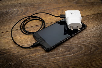 Smartphone with USB Cable and White Charger on Rustic Wooden Table
