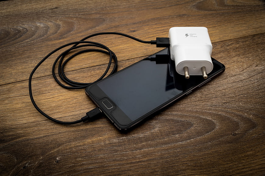 Smartphone with USB Cable and White Charger on Rustic Wooden Table