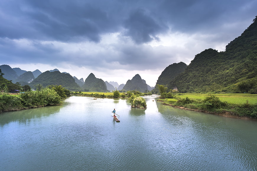 Fisherman on Bamboo Raft in Vietnamese Karst Landscape
