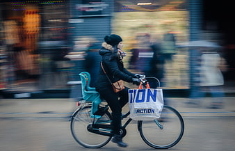 Woman cycling with shopping bags in city street
