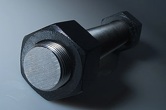 Close-up of black hex bolt and nut on gray background