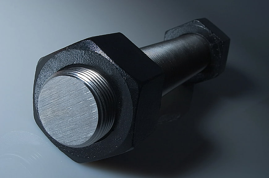 Close-up of black hex bolt and nut on gray background