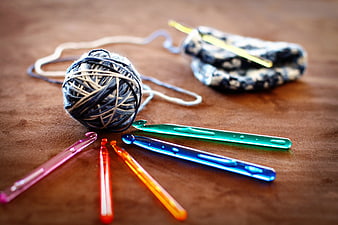 Colorful Crochet Hooks And Yarn Ball On Wooden Table