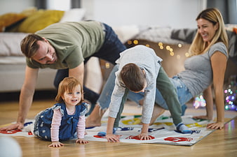 Happy family playing Twister game on living room floor