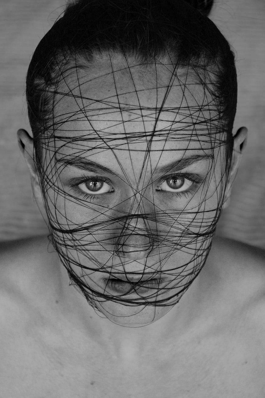 Black and white portrait of a woman with thin wires wrapped around her face