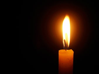 Single lit candle flame on black background