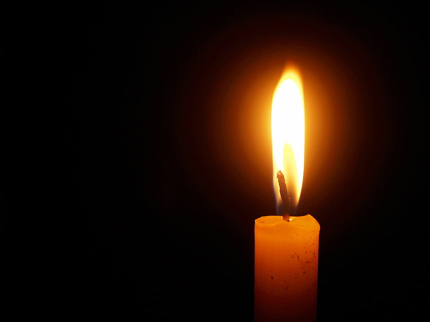 Single lit candle flame on black background