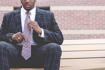 African American businessman adjusting tie on bench