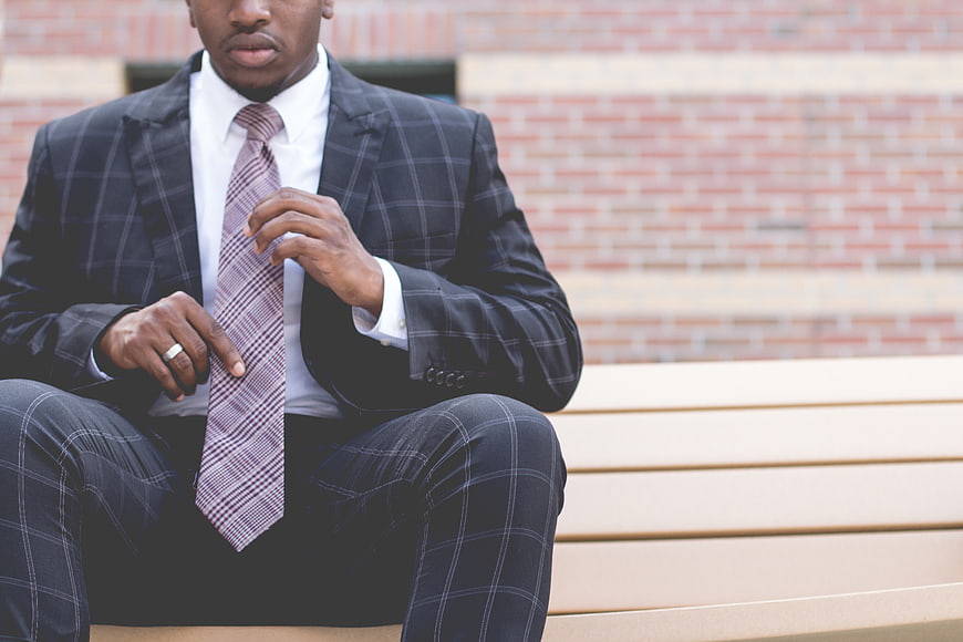African American businessman adjusting tie on bench