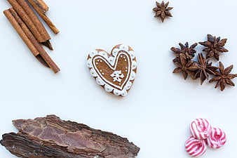 Heart-shaped gingerbread cookie with spices on white background