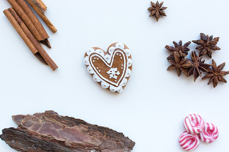 Heart-shaped gingerbread cookie with spices on white background
