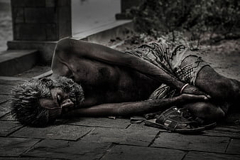 Black and white photo of elderly homeless man sleeping on pavement