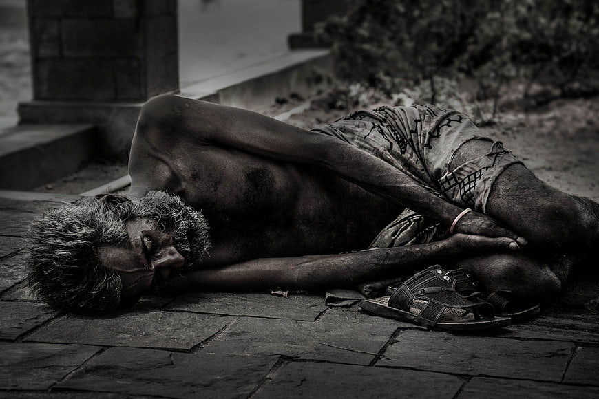 Black and white photo of elderly homeless man sleeping on pavement