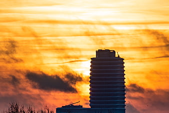 Silhouette of modern building against vibrant orange sunset sky