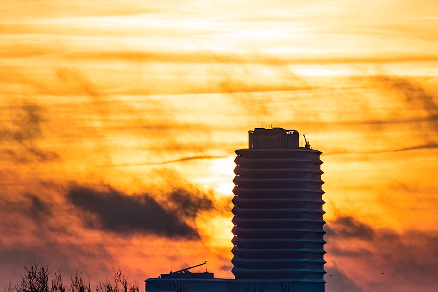 Silhouette of modern building against vibrant orange sunset sky