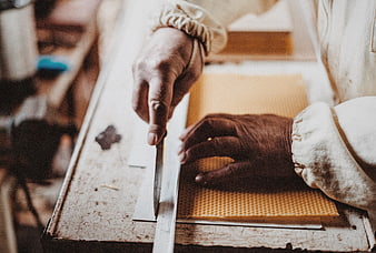 Baker cutting honeycomb with knife and ruler