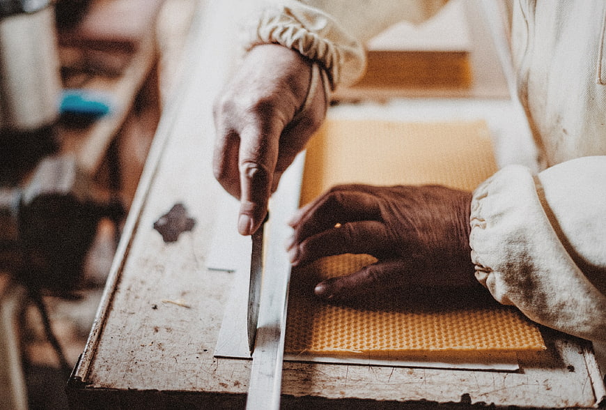 Baker cutting honeycomb with knife and ruler
