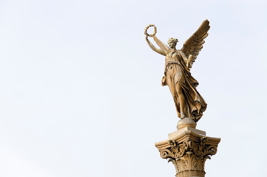 Golden Angel Statue on Ornate Column Against Sky