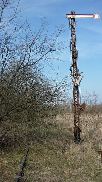 Rusty abandoned railway semaphore signal in overgrown field