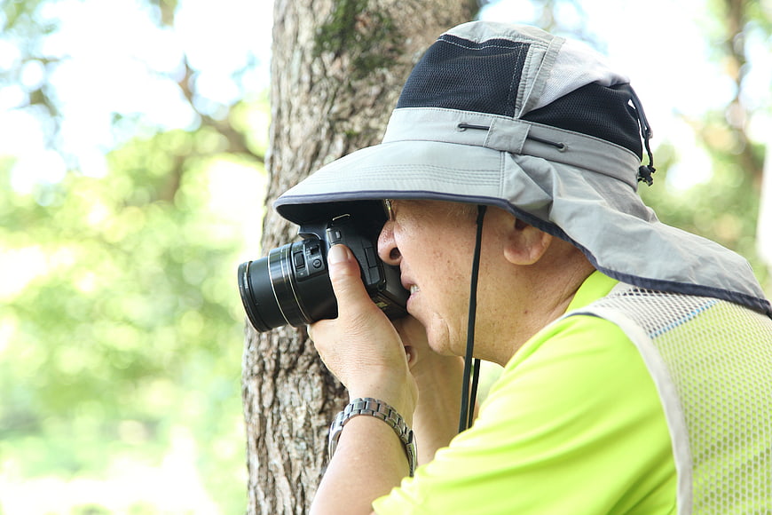 Senior man taking photos in nature with DSLR camera