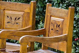 Close-up of wooden garden chairs with carved floral details
