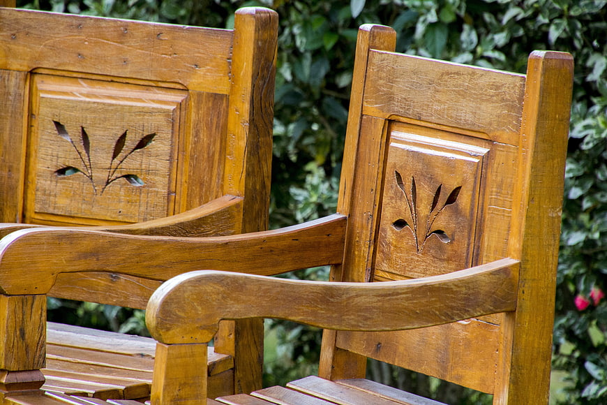 Close-up of wooden garden chairs with carved floral details