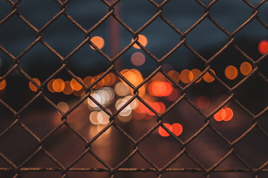 Chain link fence with blurred city lights at night