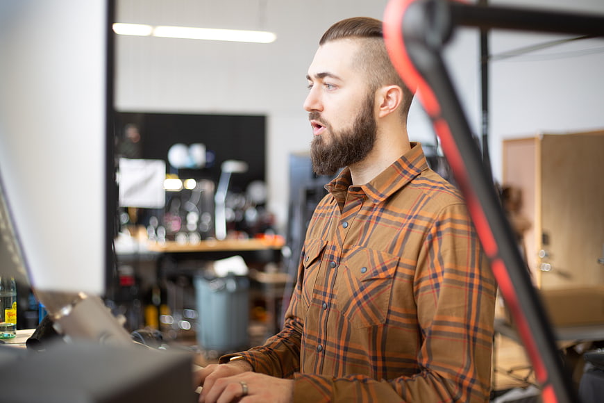 Young bearded man working at computer in creative studio
