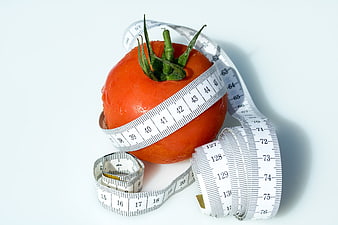 Fresh Tomato Wrapped in Measuring Tape on White Background
