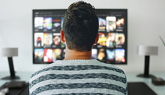 Man watching streaming service interface on large television screen