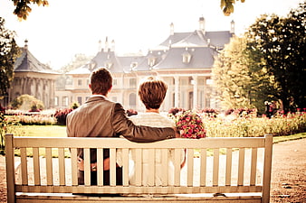 Bride and groom sitting on bench facing chateau