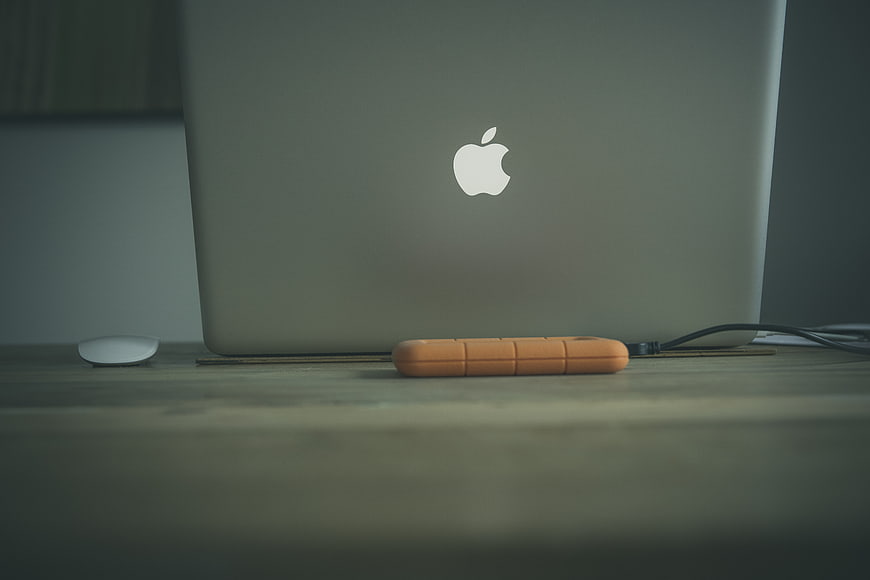Minimalist workspace with MacBook and orange tech accessory