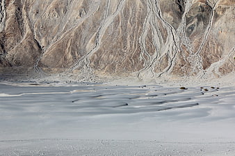 Arid desert landscape with white sand dunes and eroded canyon walls