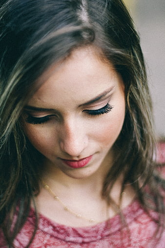 Close-up portrait of a young woman looking down with red lipstick