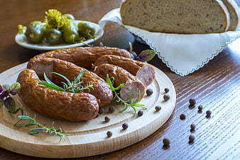 Gourmet sausages with herbs, peppercorns, and bread on wooden board