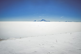 Snowy mountain peak above sea of clouds winter landscape