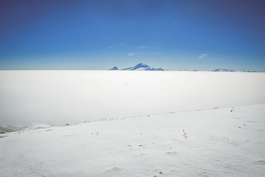 Snowy mountain peak above sea of clouds winter landscape